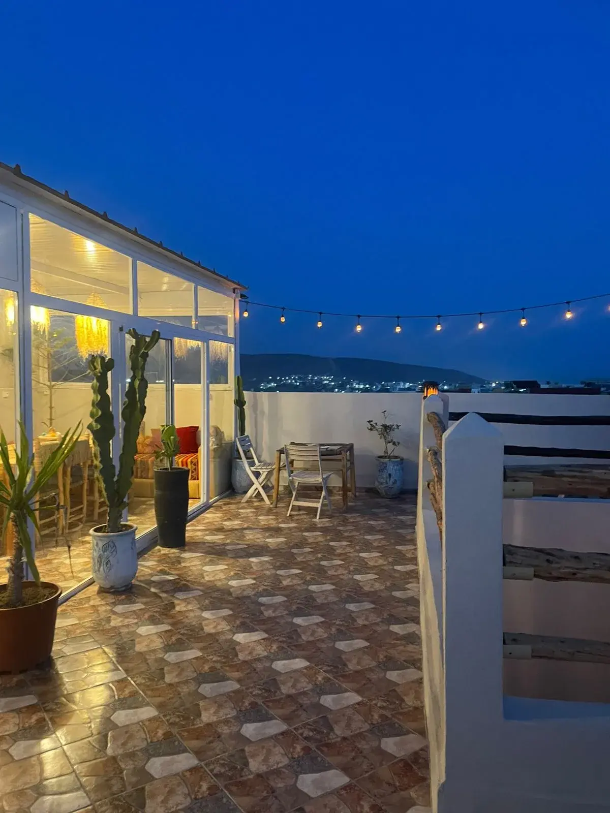 Rooftop terrace and illuminated lounge at dusk beneath a deep blue sky