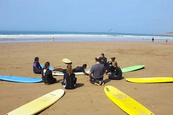 Surfers sitting on the beach among colourful boards during a group briefing